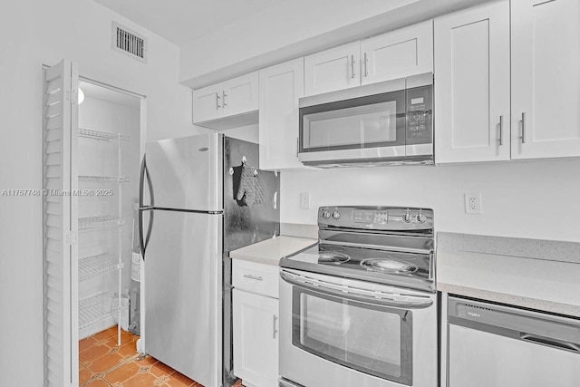 kitchen with light countertops, appliances with stainless steel finishes, visible vents, and white cabinets