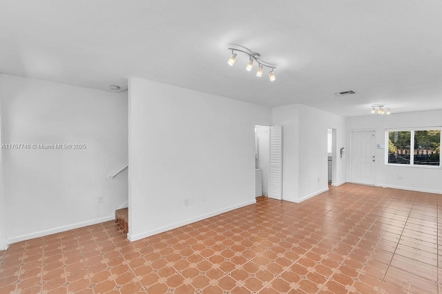 empty room with stairway, visible vents, and baseboards