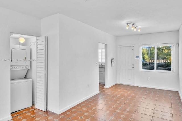 entrance foyer featuring baseboards and stacked washing maching and dryer