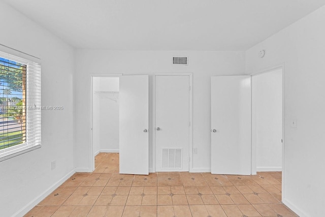 unfurnished bedroom featuring a spacious closet, a closet, visible vents, and baseboards