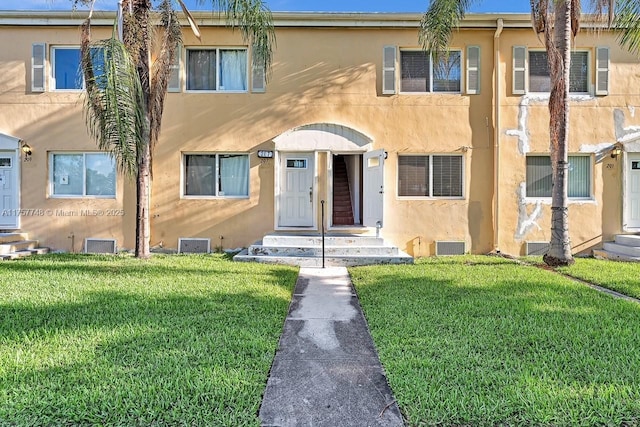 townhome / multi-family property featuring a front yard and stucco siding