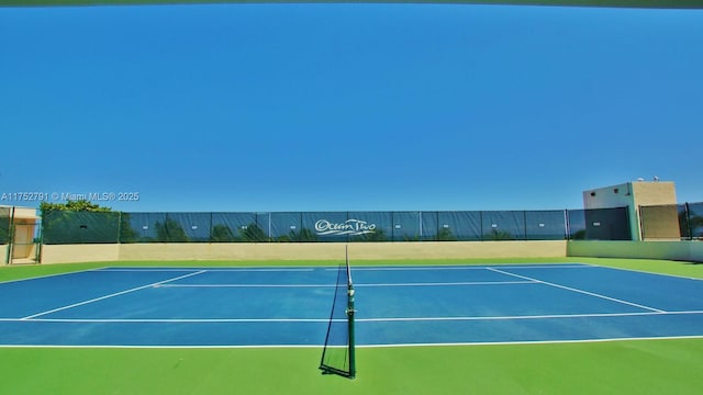 view of tennis court featuring community basketball court and fence