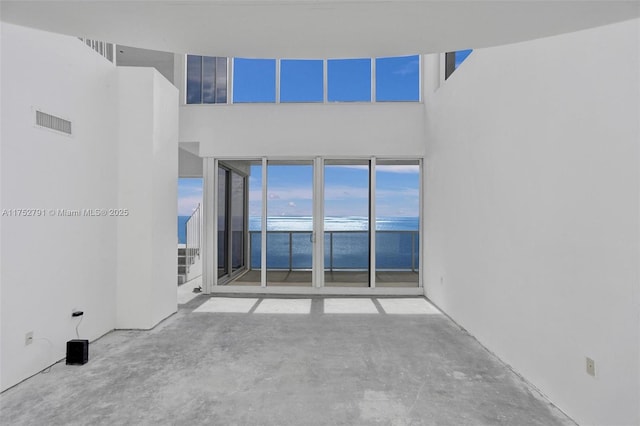 unfurnished room with concrete floors, a water view, and visible vents