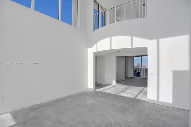 unfurnished living room featuring unfinished concrete floors and a high ceiling