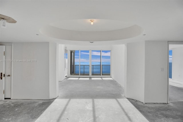 interior space with unfinished concrete floors and a tray ceiling