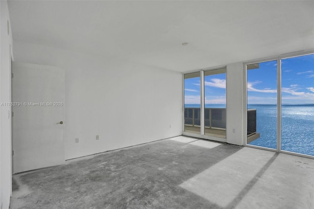 spare room with expansive windows, a water view, and unfinished concrete flooring