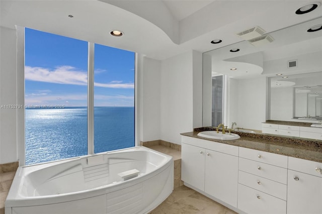 full bathroom featuring visible vents, a garden tub, vanity, and a water view