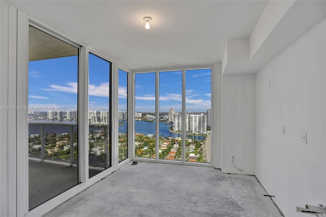 interior space with floor to ceiling windows, a water view, a city view, and unfinished concrete floors