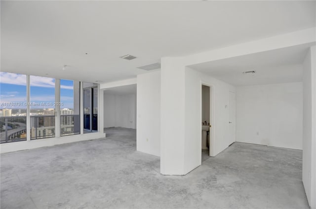 unfurnished room featuring a view of city, visible vents, and concrete flooring