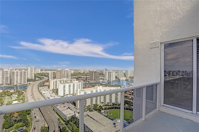 balcony featuring a water view, visible vents, and a city view