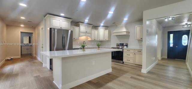 kitchen with custom exhaust hood, light wood-style floors, appliances with stainless steel finishes, and light countertops