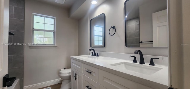 bathroom featuring baseboards, a sink, toilet, and double vanity