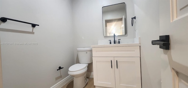 half bath featuring toilet, baseboards, and vanity