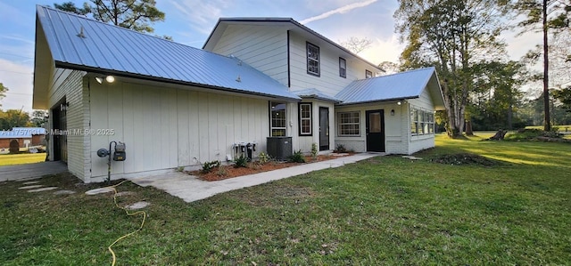 back of property with metal roof and a yard