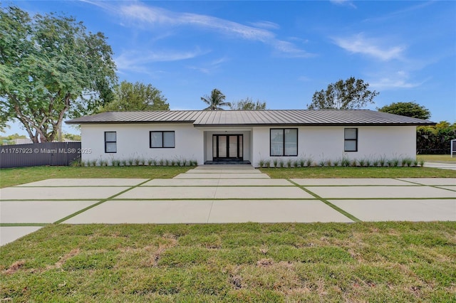 view of front of home featuring a standing seam roof, a front yard, metal roof, and stucco siding