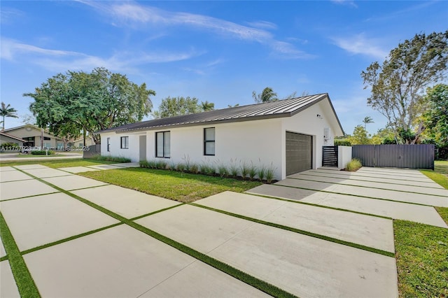 view of front of house with stucco siding, concrete driveway, a standing seam roof, metal roof, and a garage