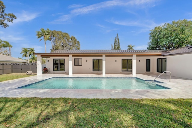 rear view of property featuring a standing seam roof, a patio area, fence, and stucco siding