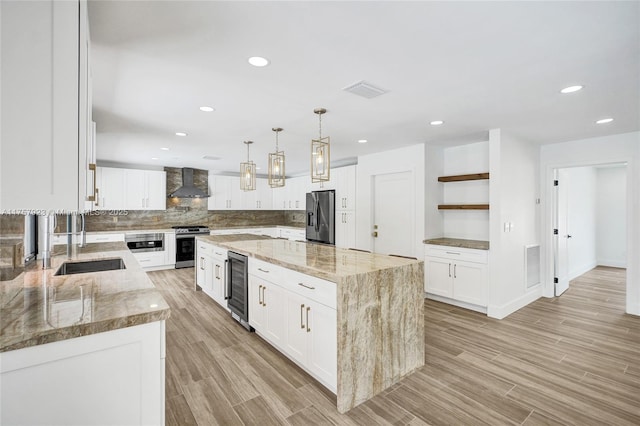 kitchen featuring beverage cooler, visible vents, wall chimney exhaust hood, appliances with stainless steel finishes, and a sink