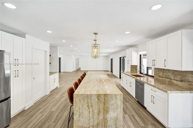 kitchen with light wood finished floors, tasteful backsplash, open floor plan, stainless steel appliances, and a sink