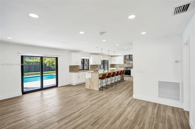 kitchen with a breakfast bar, visible vents, fridge with ice dispenser, and decorative backsplash