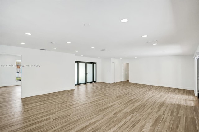 empty room with light wood-type flooring, baseboards, and recessed lighting