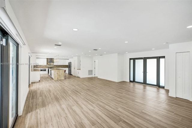 unfurnished living room with french doors, light wood-type flooring, visible vents, and recessed lighting