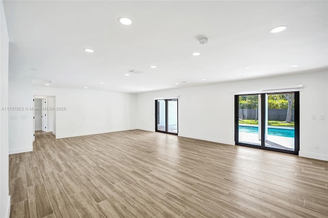 empty room with light wood-style flooring, baseboards, and recessed lighting