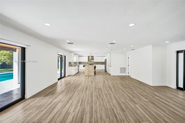 unfurnished living room with light wood-type flooring, baseboards, visible vents, and recessed lighting