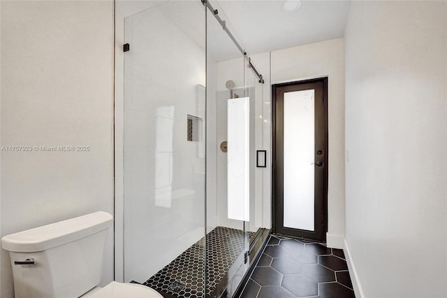 full bathroom featuring a shower stall, toilet, and baseboards