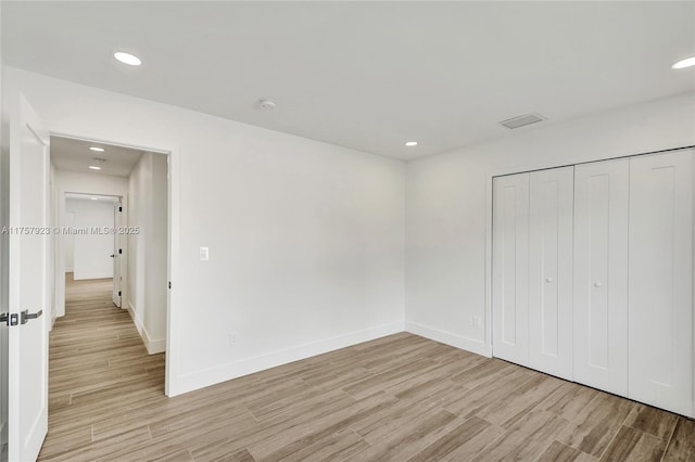 unfurnished bedroom with recessed lighting, a closet, light wood-style flooring, and baseboards