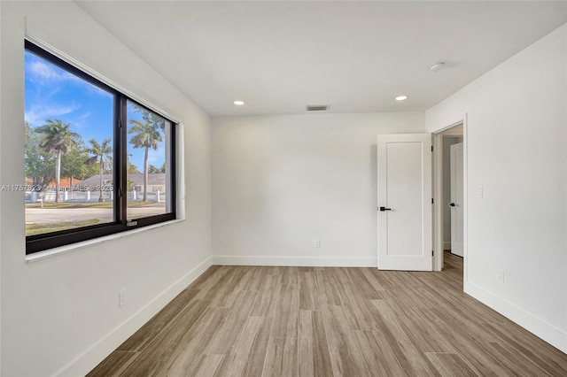 unfurnished room featuring baseboards, visible vents, wood finished floors, and recessed lighting