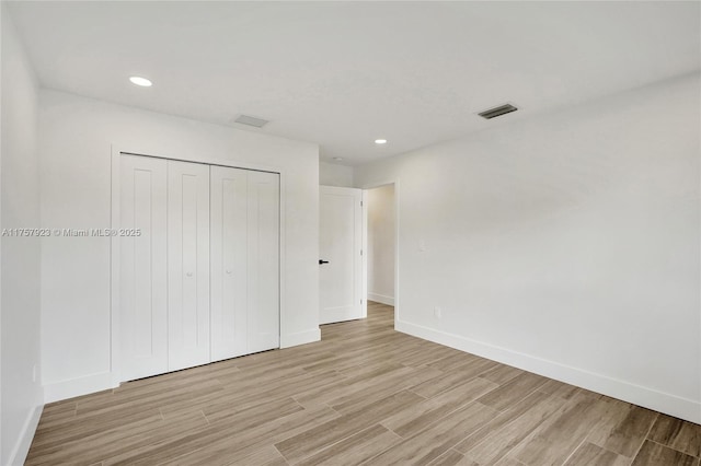 unfurnished bedroom with recessed lighting, visible vents, baseboards, a closet, and light wood finished floors