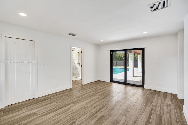 empty room with light wood-style flooring, visible vents, and baseboards