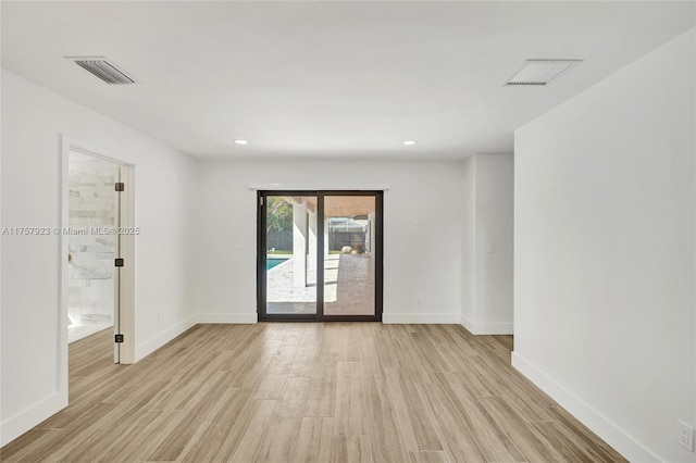 empty room featuring light wood-style floors, baseboards, and visible vents