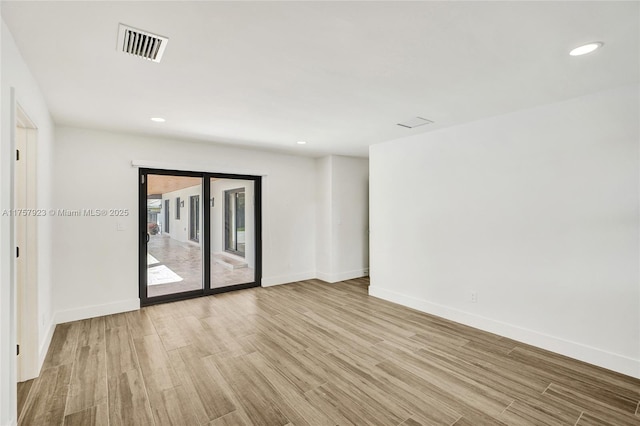 spare room featuring recessed lighting, wood finished floors, visible vents, and baseboards