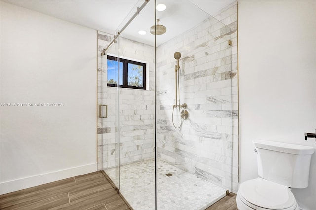 bathroom with toilet, a stall shower, baseboards, and wood finished floors