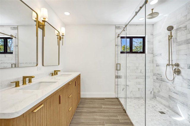 full bath featuring a sink, a shower stall, baseboards, and double vanity