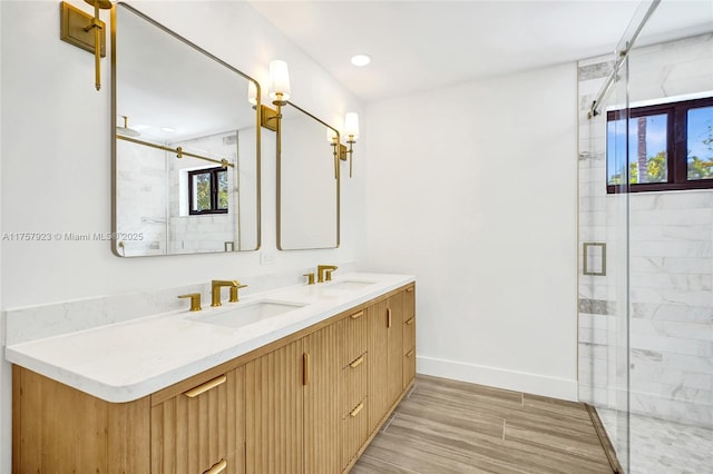 full bathroom featuring a sink, a shower stall, baseboards, and double vanity