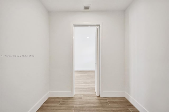 spare room with baseboards, visible vents, and wood finished floors