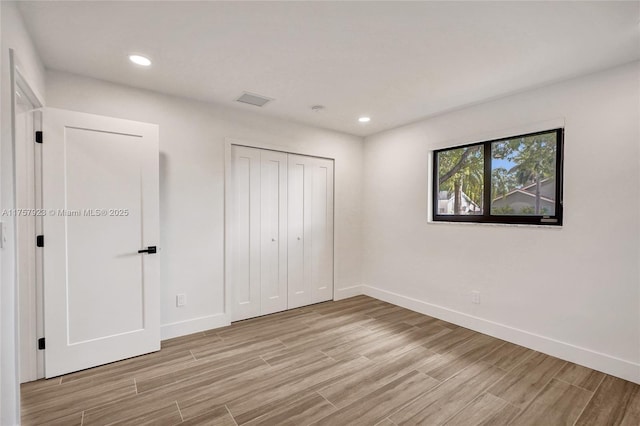 unfurnished bedroom with light wood-type flooring, baseboards, and recessed lighting