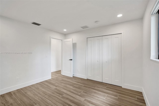 unfurnished bedroom with baseboards, visible vents, wood finished floors, a closet, and recessed lighting