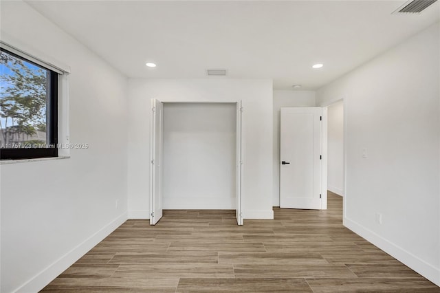 unfurnished bedroom with light wood finished floors, visible vents, and baseboards