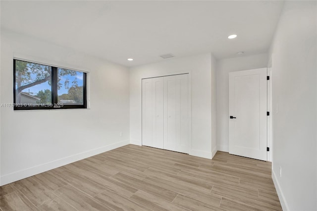 unfurnished bedroom featuring recessed lighting, a closet, baseboards, and light wood finished floors