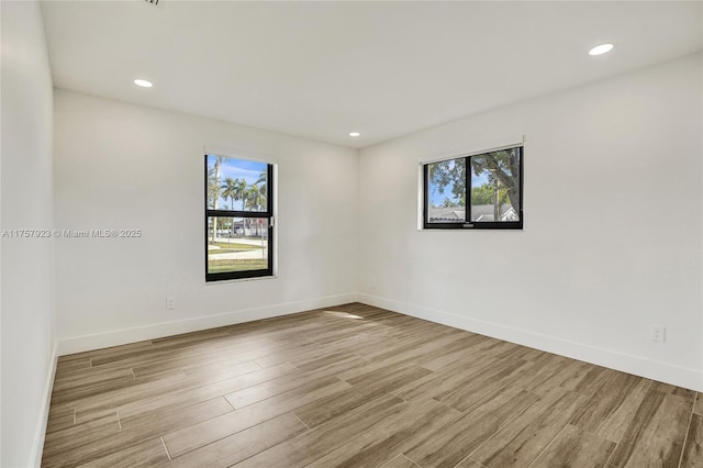 spare room with plenty of natural light, baseboards, wood finished floors, and recessed lighting