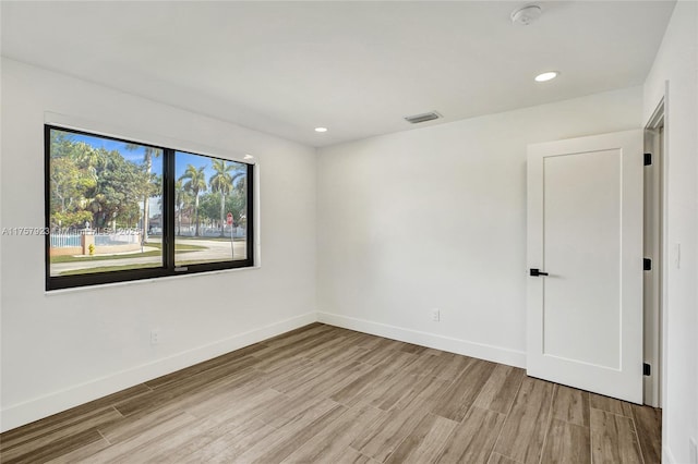 unfurnished room featuring recessed lighting, light wood-type flooring, and baseboards