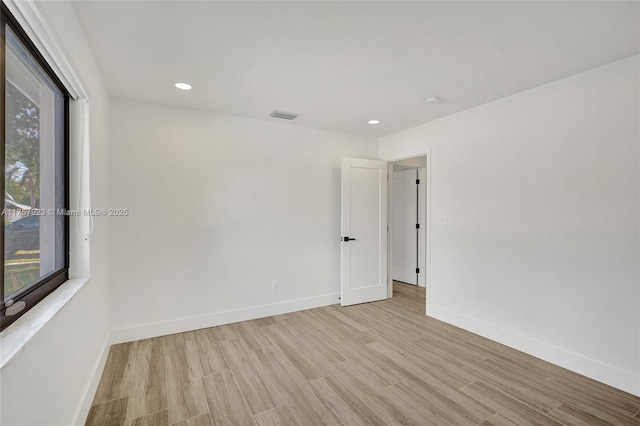 empty room with wood finished floors, visible vents, and baseboards