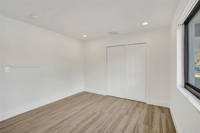 unfurnished bedroom with a closet, recessed lighting, wood finished floors, and baseboards