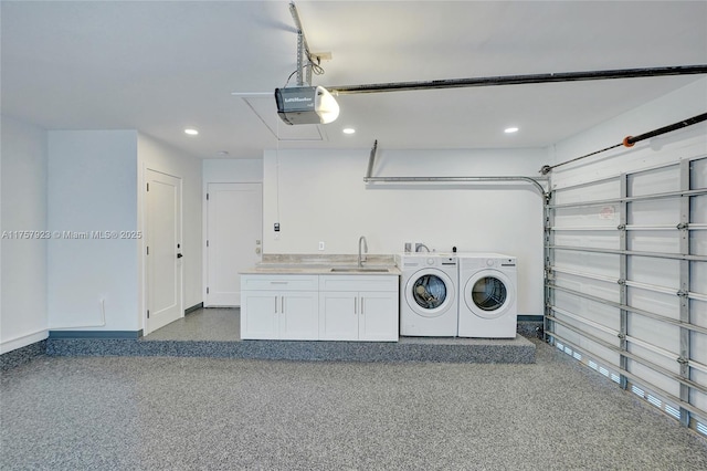 garage with baseboards, a garage door opener, washing machine and dryer, a sink, and recessed lighting