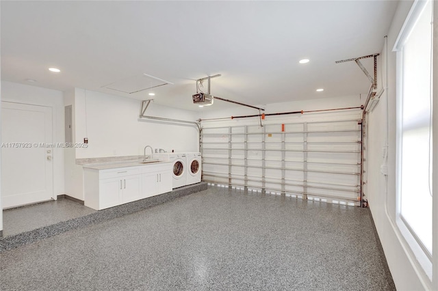 garage with a garage door opener, recessed lighting, a sink, and washer and dryer