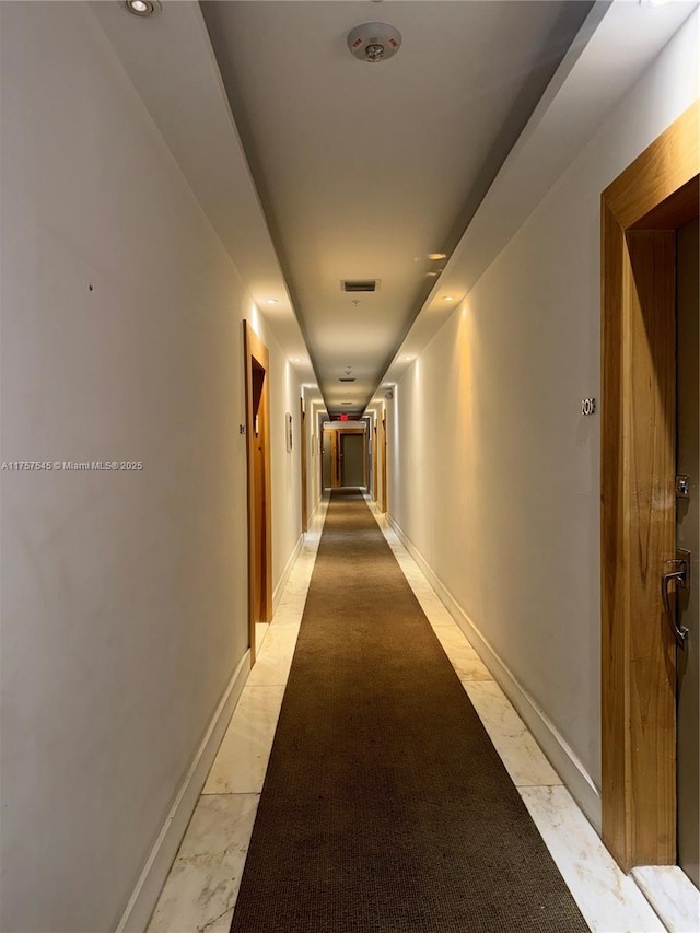 corridor featuring marble finish floor, baseboards, and visible vents